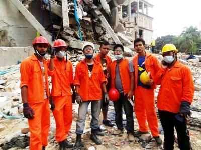Standing on rubble, Adventist Youth volunteers assist in a rescue operation after a garment factory in Savar near Dhaka Bangladesh collapsed on April 24, killing 400 and injured over 2,000. [photo by Flabian Shaikat Sikder]