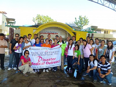 After a relief operation, a disaster response team from Bacolod Adventist Medical Center pose in front of the stage of what used to be a covered court/gymnasium in Cadiz City, one of the places hit by Typhoon Haiyan with its fast winds tearing apart houses and buildings on November 8 (Photo provided by Jo Anne Amparo)