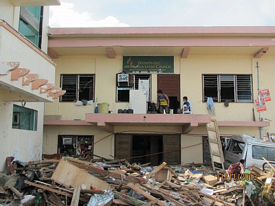 The Adventist church headquarters in east Visayas located in Tacloban surrounded by huge piles of debris in the aftermath of typhoon Haiyan that hit the city on November 8. Church leaders & members now try to clear the area surrounding the office to provide a place for relief operation. [photo by Luna Casio]