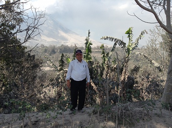 Pastor J.S. Peranginangin, president of the Adventist church mission in west Indonesia stands from a safe distance away from Mr. Sinabung, surrounded by vegetation covered by volcanic ash.